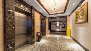 A modern elevator area with marble flooring and a chandelier. - Jianglong Hotel (Dongguan Houjie Wanda Plaza) (Dongguan)