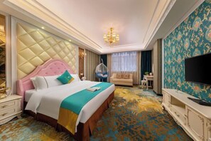Una habitación de hotel con una cama grande, televisión, candelabro y alfombra estampada.