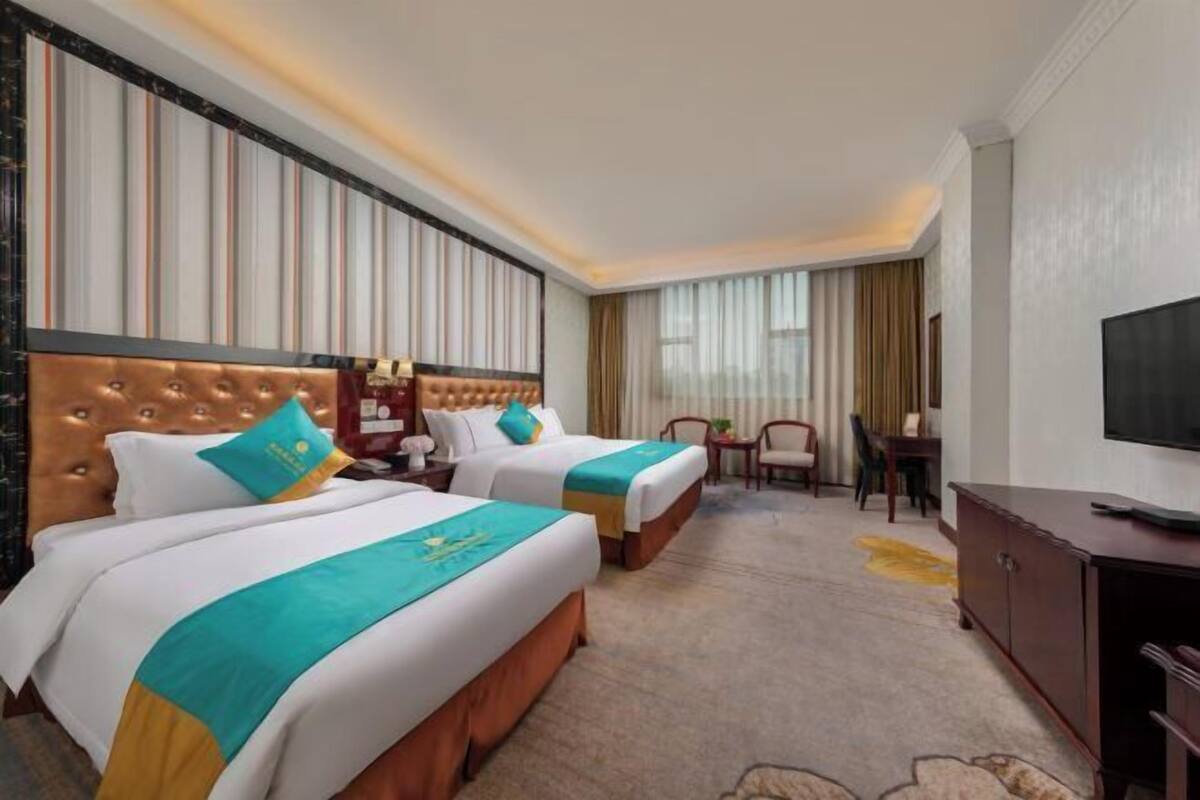 A hotel room with two beds, a TV, a desk, and a chair.