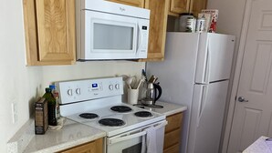 Une cuisine avec des meubles en bois, un fourneau blanc, un four à micro-ondes et un réfrigérateur.