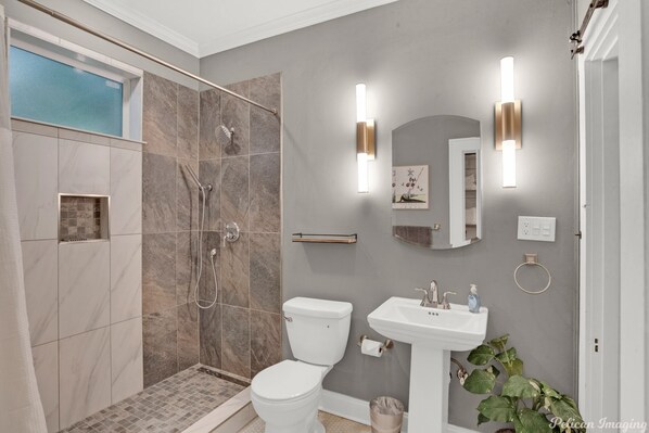 Une salle de bain moderne avec une douche à l’italienne, des toilettes et un lavabo.