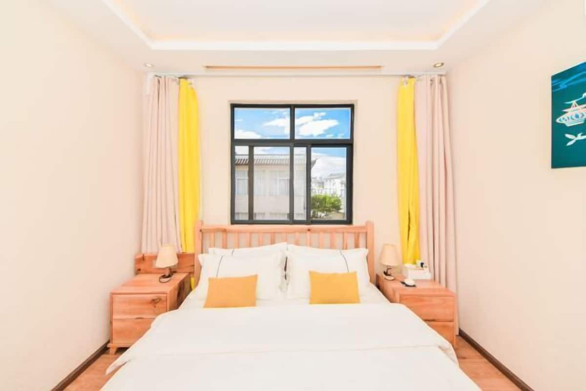 A hotel room with a bed, two bedside tables, a window, and curtains.