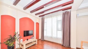 Een moderne woonkamer met een houten vloer, een flatscreen televisie aan de muur, een houten bankje en een potplant.