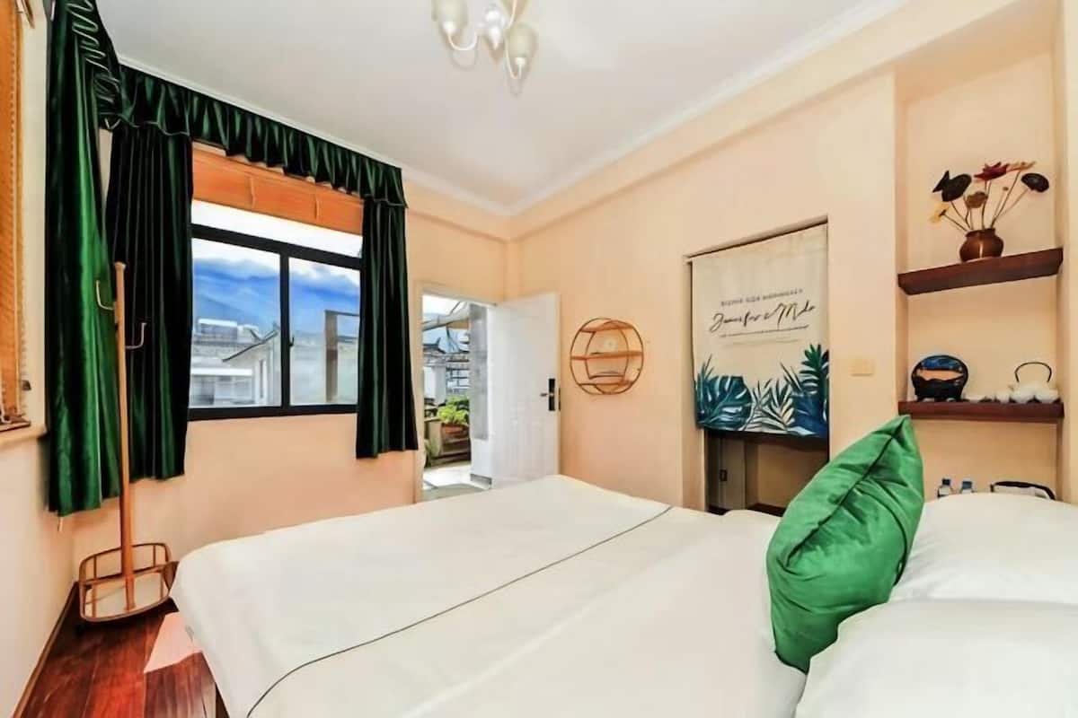 A hotel room with two beds, a window with curtains, a door leading outside, and a wall with a decorative item.