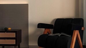 A modern room with a black armchair, a wooden side table, and a rattan drawer unit. - Golden Silver Bay Seaview Hotel (Dali Shuanglang Branch) (Dali City)