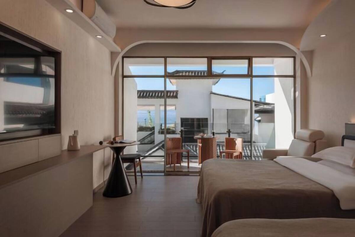 Ein modernes Hotelzimmer mit einem großen Bett, einem Schreibtisch und einem Balkon mit Blick.