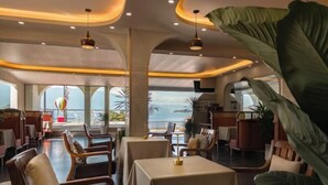 A restaurant with tables and chairs, a view of the sea, and a large plant. - Golden Silver Bay Seaview Hotel (Dali Shuanglang Branch) (Dali City)