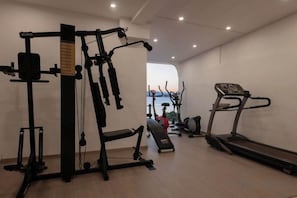 A gym with exercise equipment including a treadmill, weight machines, and a bench.
