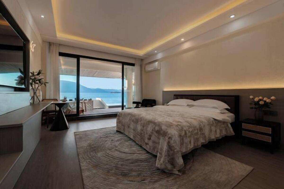 Ein modernes Hotelzimmer mit einem großen Bett, einem Schreibtisch und Blick aufs Meer.