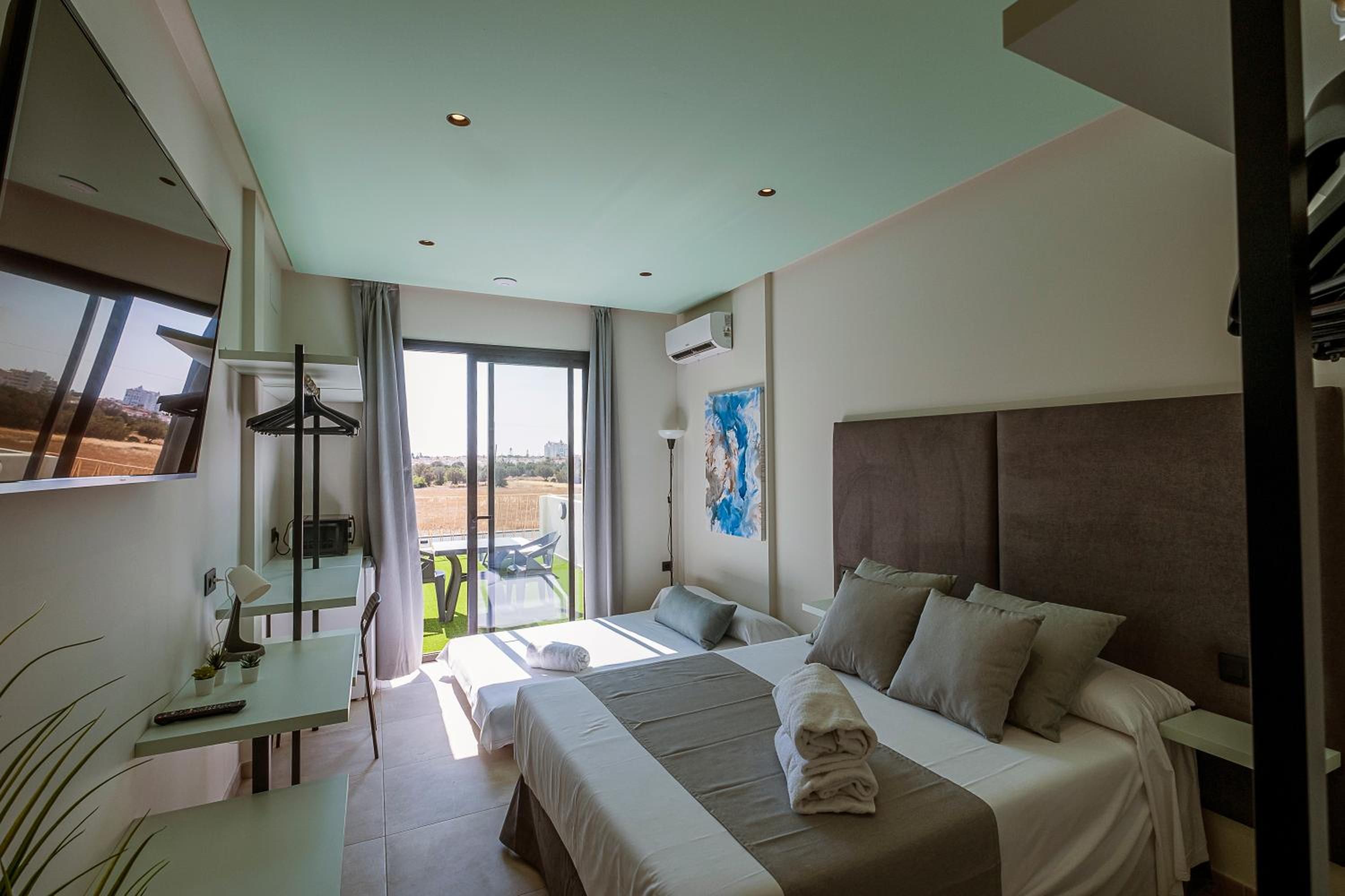 Habitación de hotel moderna con una cama grande, un escritorio y un balcón con vistas.