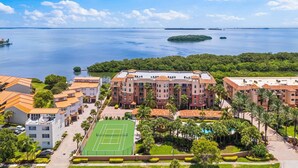 A hotel with multiple buildings, a tennis court, and a view of a large body of water with islands. - Tortuga Shoals (Tierra Verde)
