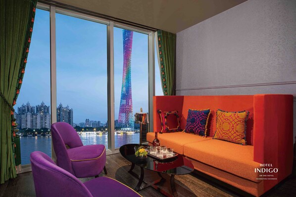 Ein modernes Hotelzimmer mit einem großen Fenster, das einen Blick auf den Stadtpanoramahimmel und einen markanten Turm bietet.