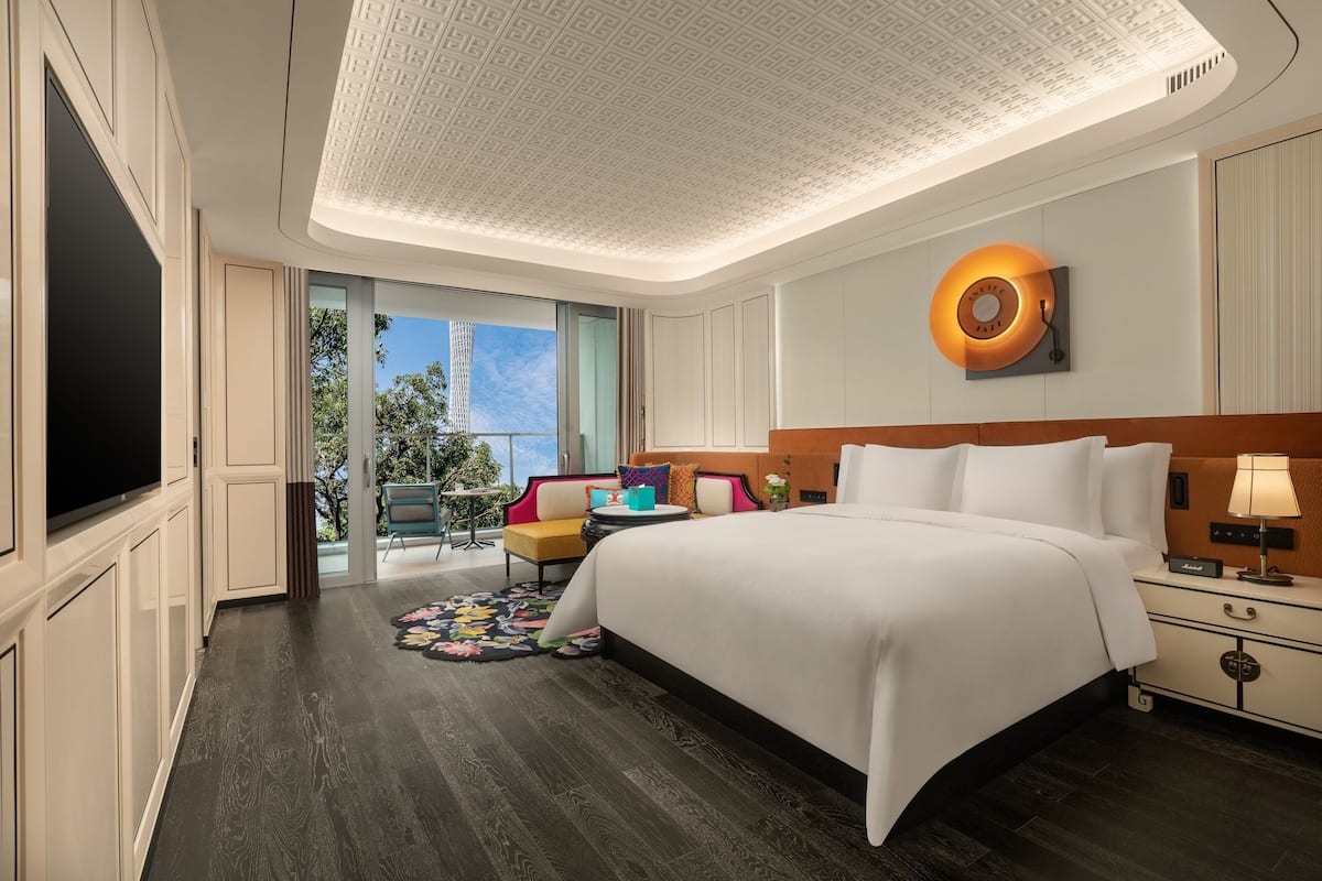 Habitación de hotel con una cama grande, un televisor de pantalla plana, un aplique de techo y vistas al exterior.