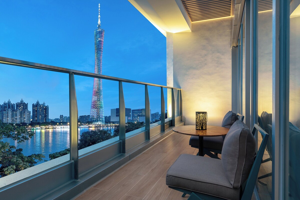 Ein Balkon mit Blick auf einen hohen Turm, einem Tisch mit Stühlen und einem Geländer.