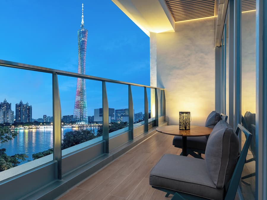Un balcon donnant sur une haute tour, une table avec des chaises et une rambarde.
