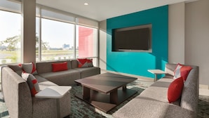 Una sala de estar moderna con un sofá modular, una mesita de centro y un televisor de pantalla plana montado en una pared de acento color turquesa.