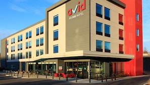 Un moderno edificio de hotel con un llamativo letrero 'avid', grandes ventanales y un área de entrada cubierta.