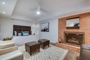 Een moderne slaapkamer met een groot bed, een open haard en uitzicht op de stad.
