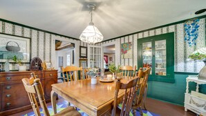 A dining area with a wooden table and chairs, a chandelier, and a patterned floor. - Pet-Friendly Smoky Mountain Getaway w/ Fire Pit! (Clyde)