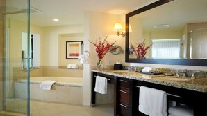 A modern bathroom with a glass shower enclosure, a large bathtub, and a vanity with a mirror.