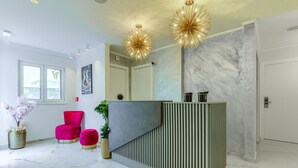 A modern reception area with a marble floor, a central counter, and a large mirror. - Irini Luxury Rooms (Split)