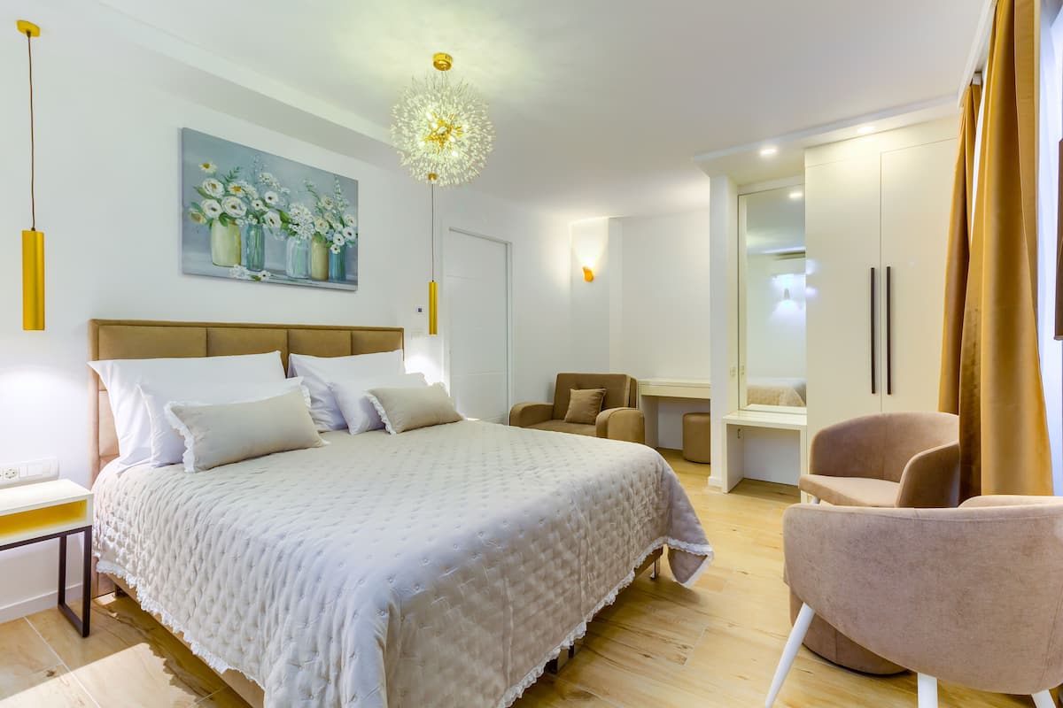 A modern bedroom with a large bed, a desk, a chair, and a wardrobe.