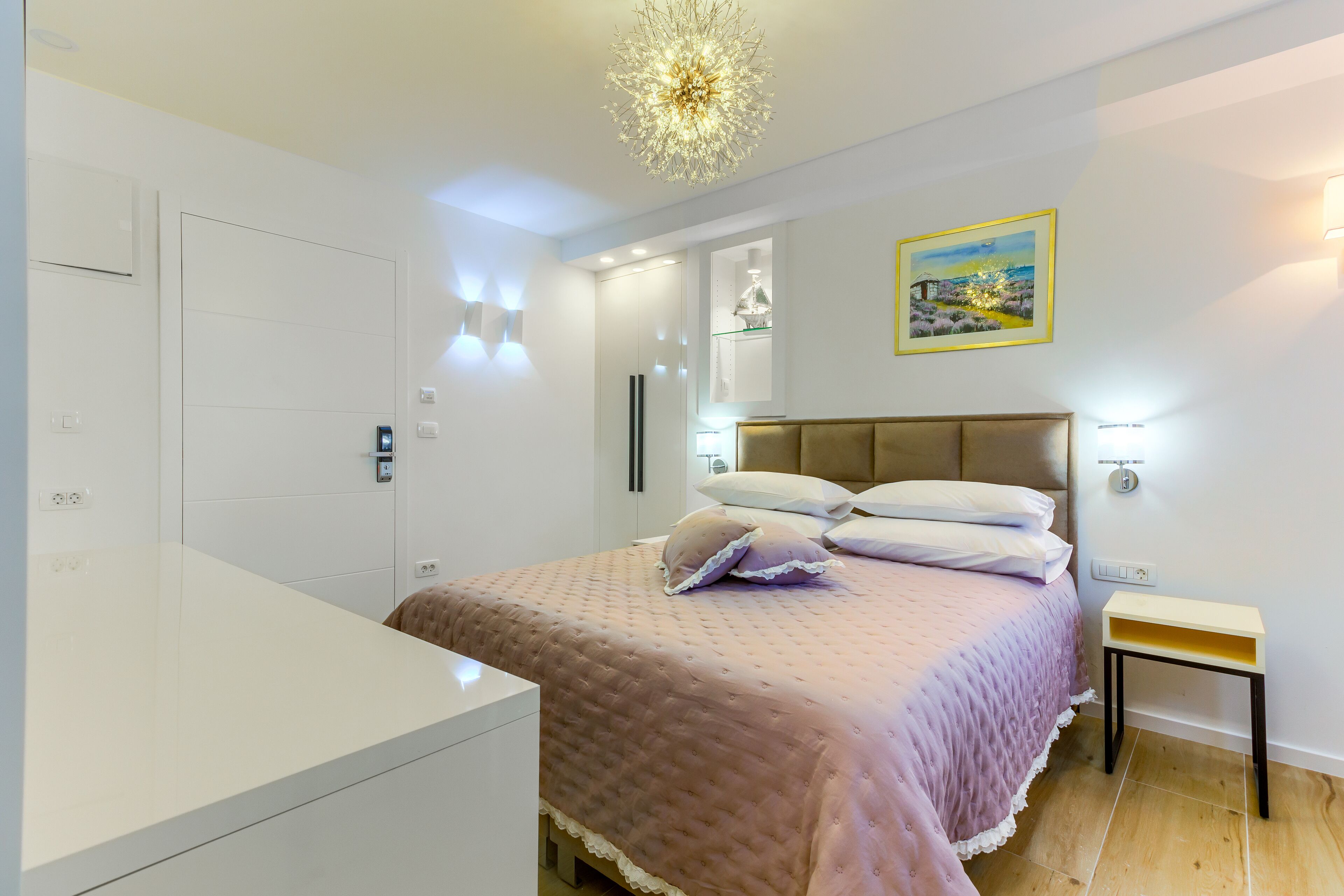 Un dormitorio moderno con una cama grande, una mesita de noche y una lámpara decorativa en el techo.