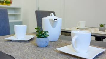 A table with two white cups and a white pitcher on a tablecloth.