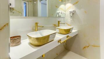 Un baño con dos lavamanos, detalles dorados y un espejo grande.