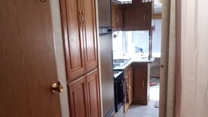 Ein Flur, der zu einer Küche mit Holzausstattung, einem Kühlschrank und einem Spülbecken führt.