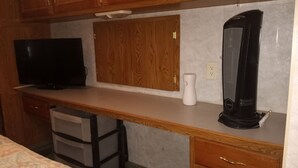 Ein kleines Hotelzimmer mit einem Holztisch, einem Fernseher, einer Heizung und einer kleinen Ablagefläche.