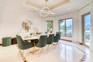 Un comedor moderno con una mesa redonda, sillas tapizadas en verde y un amplio ventanal con vistas al exterior.
