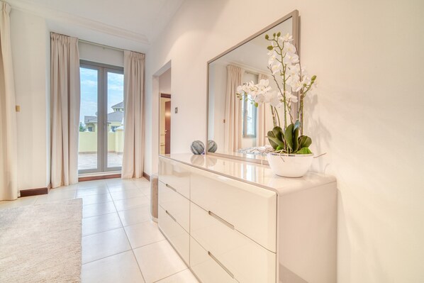 A modern bathroom with a large mirror, white cabinets, and a potted orchid.