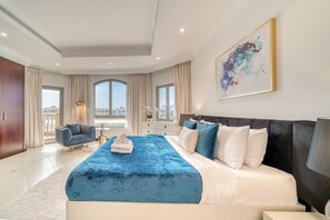 A modern hotel room with a large bed, a seating area, and a view of the city.