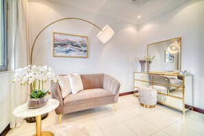 A modern living room with a beige sofa, a round coffee table, a gold-framed mirror, and a white floor lamp. - Beachfront 5BR Villa w/ Private Pool at the Palm (Dubai)