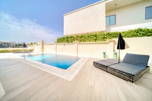 A modern outdoor pool area with a lounge chair and a small table.