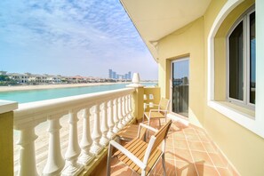 Ein Balkon mit Blick auf Strand und Meer, ausgestattet mit Geländer, Tisch und zwei Stühlen.