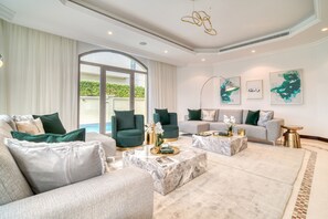 Un salón amplio con un ventanal grande, dos sofás, una mesa de centro y cojines decorativos.