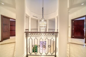 A grand hallway with a central chandelier, white columns, and wooden doors.