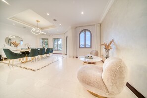A spacious living room with a dining area, large windows, and modern furniture.