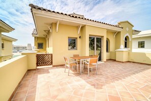 A patio with a table and chairs, a wooden fence, and a tiled floor. - Beachfront 5BR Villa w/ Private Pool at the Palm (Dubai)