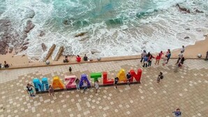 En strand med ordet "MAZATLAN" stavet i farverige bogstaver i sandet.