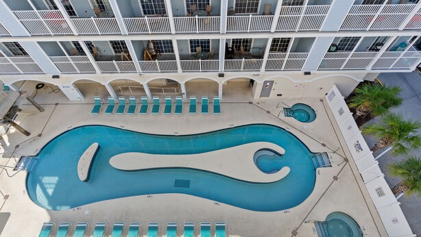 A large pool with multiple lounge chairs and a small hot tub. - bees knees (Myrtle Beach)