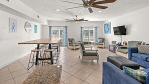 A spacious living area with a dining table, multiple chairs, sofas, and ceiling fans. - bees knees (Myrtle Beach)