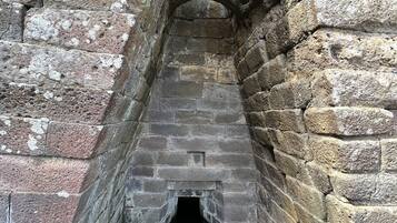 A narrow stone passageway with an arched top and a small opening at the end.
