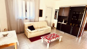 A living room with a sofa, a coffee table, a dining table, and a kitchen area with cabinets and a refrigerator. - HOUSE SEA MOUNTAIN (Bonarcado)