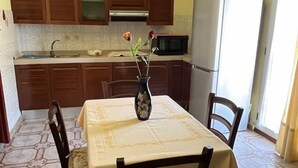 A dining area with a table set for four, surrounded by wooden chairs. A vase with flowers is placed on the table. - HOUSE SEA MOUNTAIN (Bonarcado)
