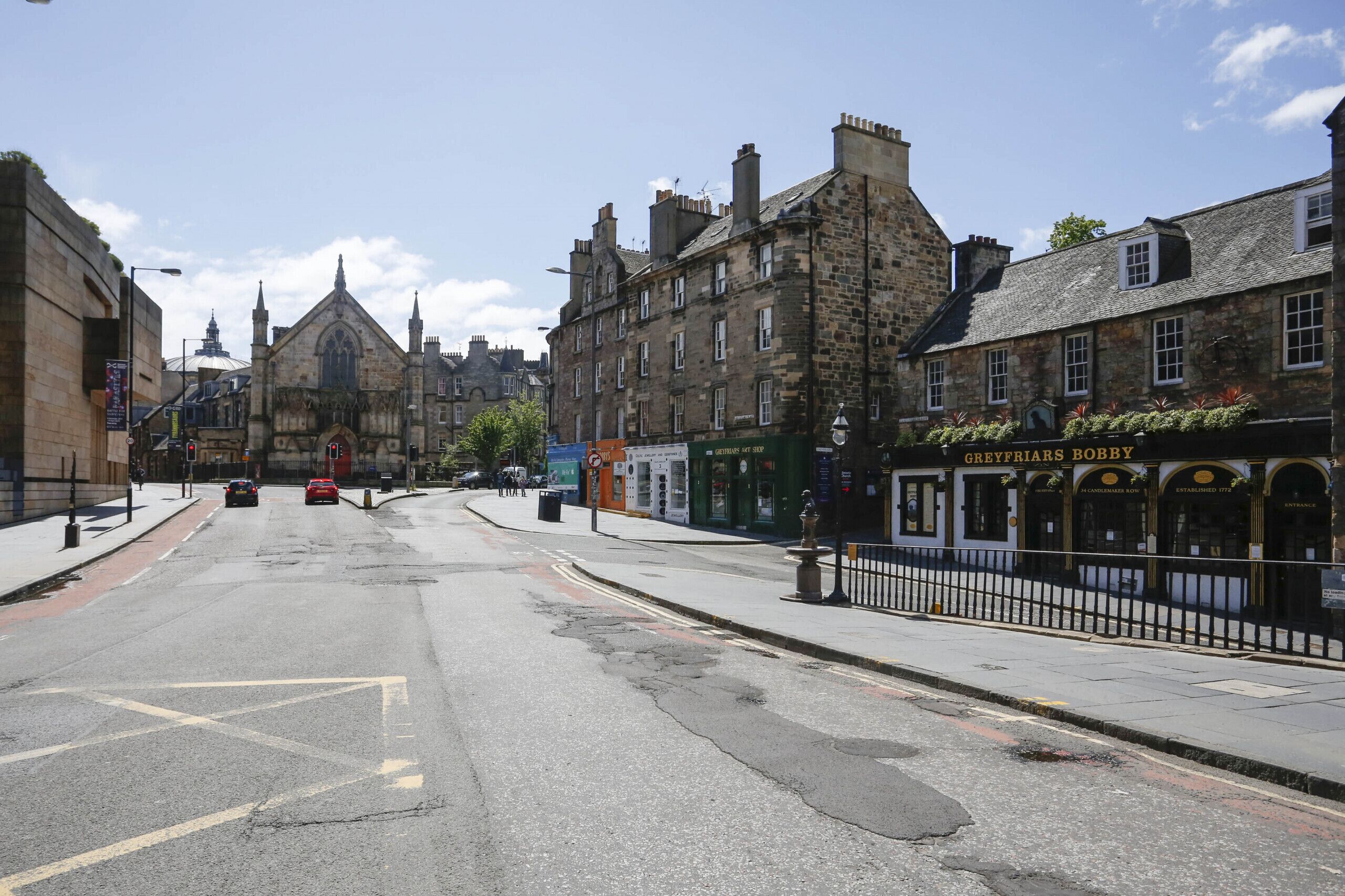 A street with historic buildings, a bus stop, and a shop named 'Greyfriars Bobby'.