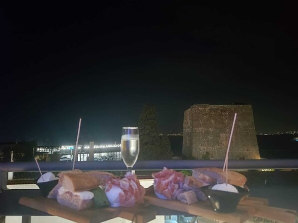A table with food and a glass of water, overlooking a cityscape at night.