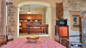 Une cuisine chaleureuse avec un mur en pierre, des armoires en bois et une table sur laquelle se trouve un panier de fruits.